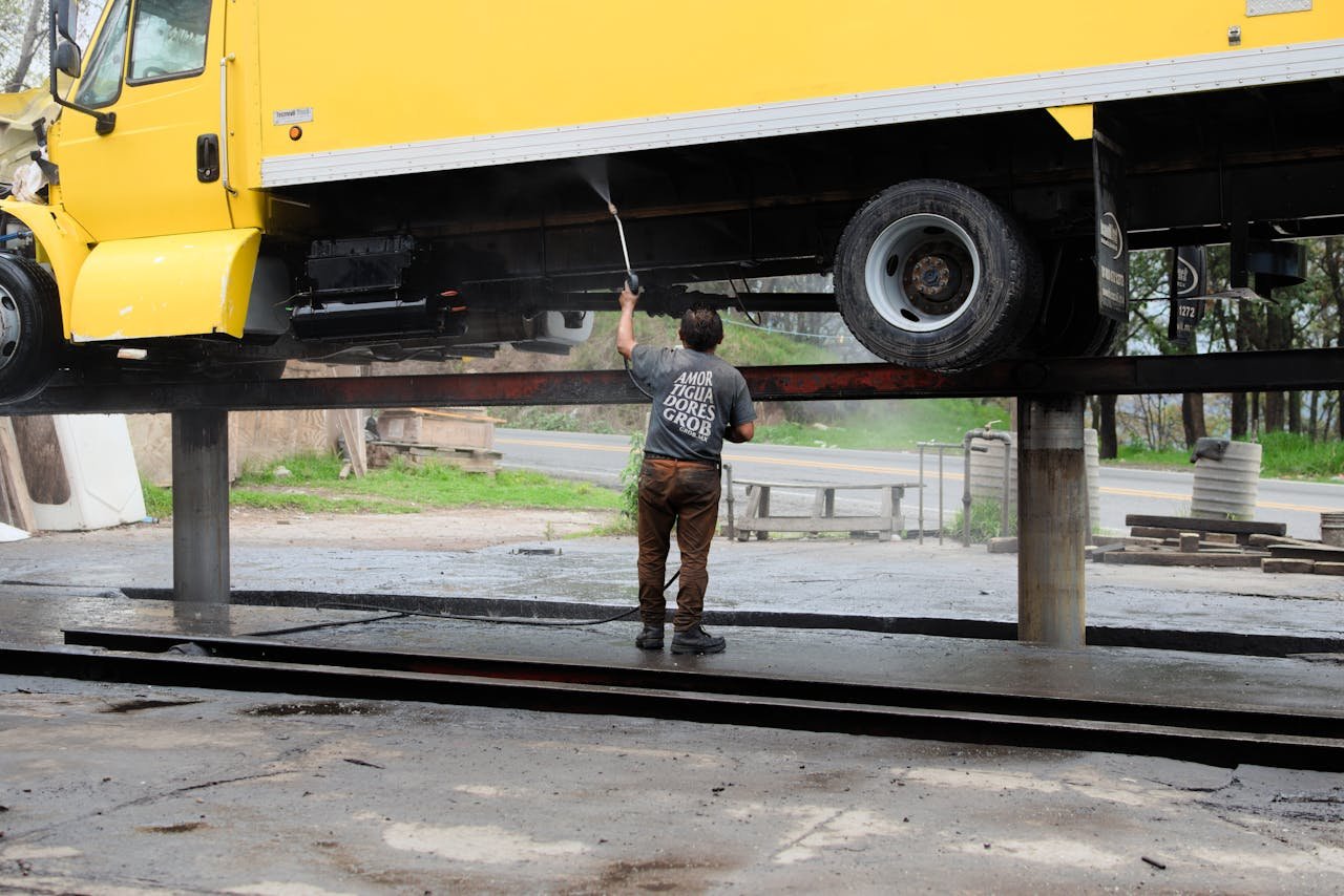 Crafting Captivating Headlines: Your awesome post title goes here A worker power washes the underside of a raised yellow truck at an outdoor service station.