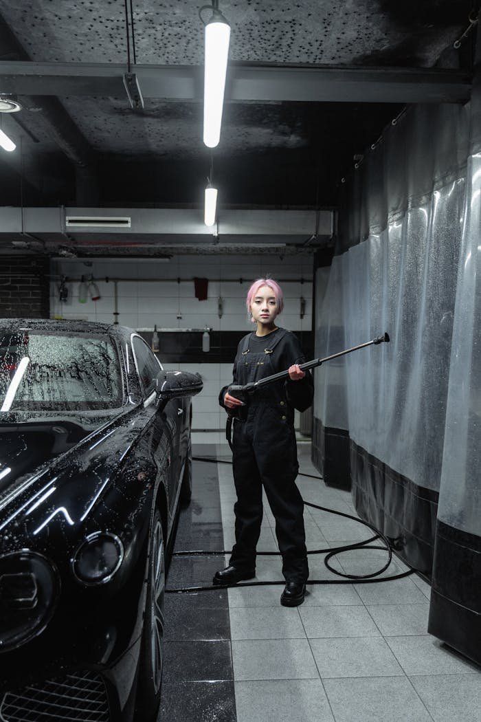 The Art of Drawing Readers In: Your attractive post title goes here Woman in uniform using power spray at indoor car wash, detailing black luxury car.
